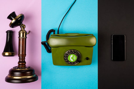 Old brown vintage telephone along with a wired green telephone and mobile phone on various color backgrounds. The concept of development of telephone communicationsの写真素材