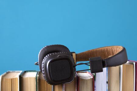 headphones and books but against blue background, concept of audio books, listening to a book.の写真素材