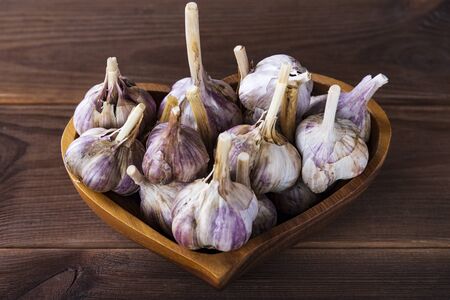 garlic in a plate in the form of a heart on a wooden table, top view.の写真素材