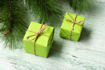 Christmas composition. Green gift boxes under the Christmas tree on a wooden floor near fir branches. View from above. a Christmas gift.の写真素材