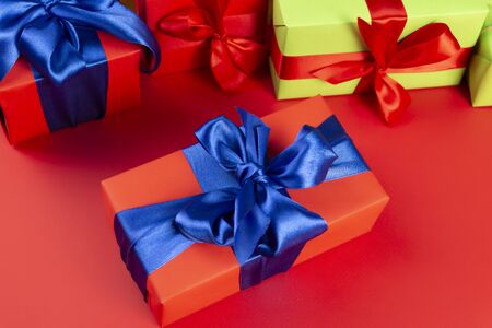 Red gift box with a blue ribbon on a red background. Lots of Christmas gift boxes.の写真素材