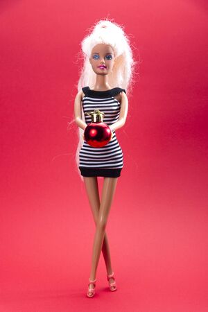 Doll with a live Christmas tree in hand, dressed in a black and white dress on a red background, Christmas compositionの写真素材