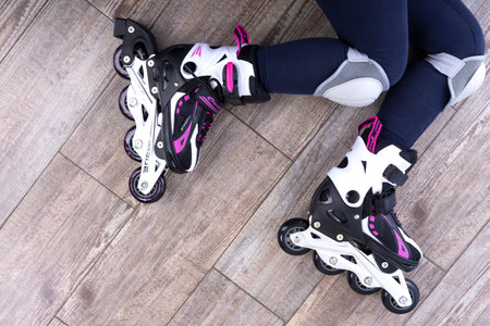 Minsk, Belarus, October 20, 2019. Childrens legs in pink roller skates on a wooden floor