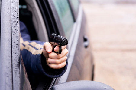 Man with a gun driving a car, male hand with a gun.