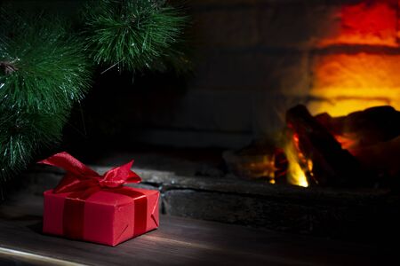 Christmas composition, gift under the tree near a burning fireplace, close-up.の写真素材