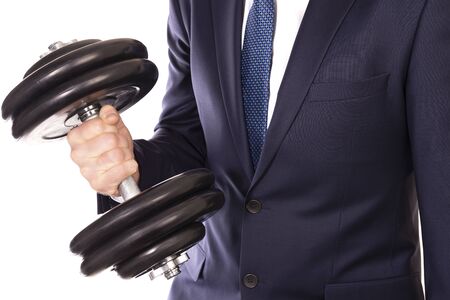 Businessman in a suit holds a dumbbell on a white backgroundの写真素材