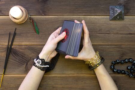 The hands of an oracle with cards predict fate. Draw out a card. Runic cards for fortune telling on a wooden table. Find out your fate.の写真素材