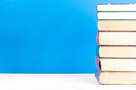 Stack of old books, blue background, free copy space. Antique old hardback books on a wooden shelf on a deck table, unmarked, empty spine. Back to school. Education.の写真素材