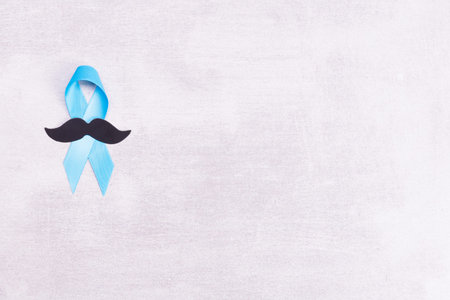 Healthcare and medicine concept - blue prostate cancer awareness ribbon and paper black mustache,...