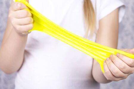 Little girl stretches yellow mucus in her hands.Children art project. DIY concept.の写真素材