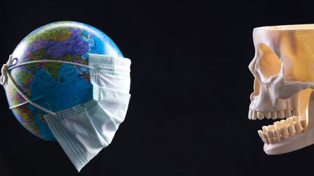 Disposable medical mask on the globe, model of the Earth. The concept of a pandemic. COVID-19, coronavirus. World epidemic of the disease. COVID Dangerous virus.の写真素材