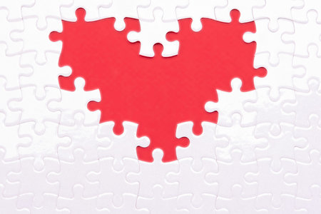 Heart from white puzzles as a symbol of love on a red background. Fans like puzzles that complement...