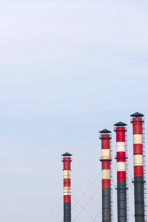 high factory exhaust pipes against a blue sky, urban air pollution.の写真素材