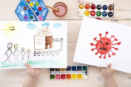 A child draws a coronovirus and his family on a piece of paper. Coronovirus and family at home. The drawing was made by a child using color paints. Childrens drawing. View from aboveの写真素材