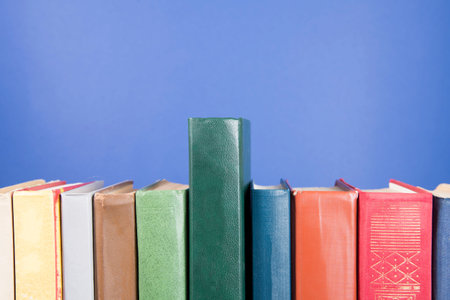Stack of old books, blue background, free copy space. Antique old hardback books on a wooden shelf...