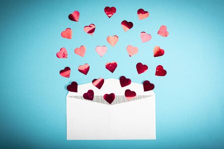 Red confetti hearts fly out of a white envelope on a light blue background. Valentine's Day. love concept Gift, message for lover.の写真素材