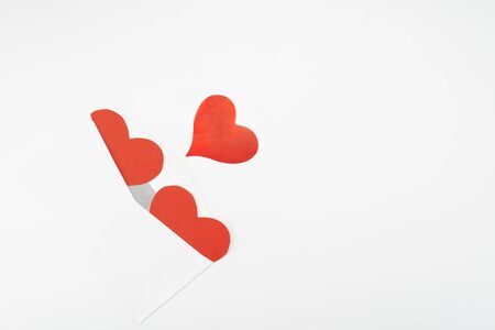 Open envelope and three red paper hearts on a white background with place for text.の写真素材