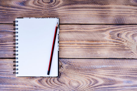 Blank notepad and pencil on wooden background