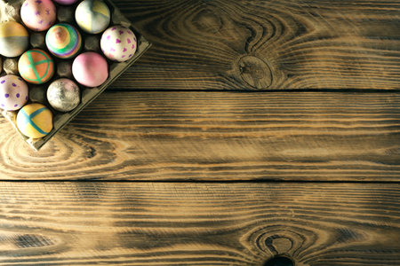 Easter eggs on a stand on wooden background with place for text, top view.
