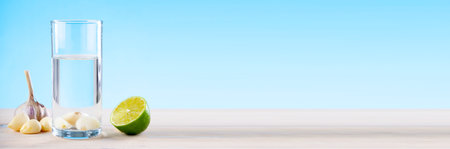 Garlic water with lime on a wooden table on a blue background, water with garlic, water with lemon, disease prevention.の写真素材