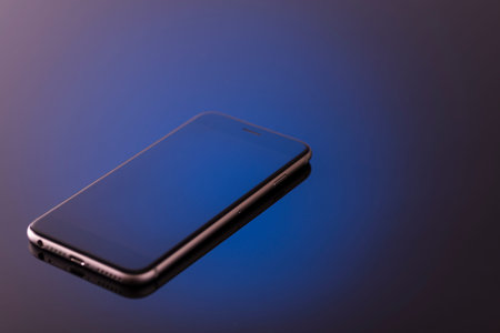 smartphone on black background toned blue, studio photo.