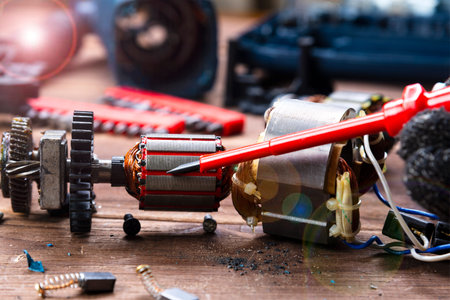 Power tool repair. Details of electrical appliance and repair tools on a wooden table in a repair...
