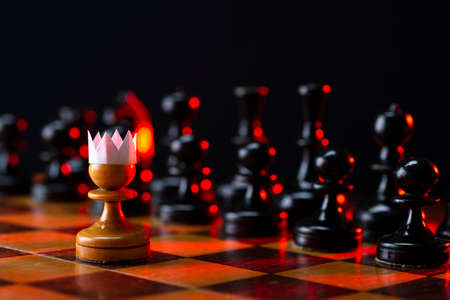 Little brave pawn wearing faux paper crown suit leading others to battle the enemy - business entrepreneur leadership concept.の写真素材