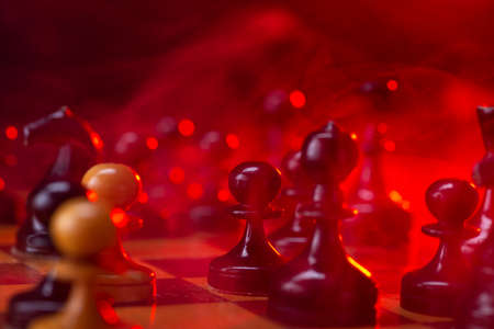 Chess fight, chess pieces on the board, toned in red. Battle fire and smoke.の写真素材