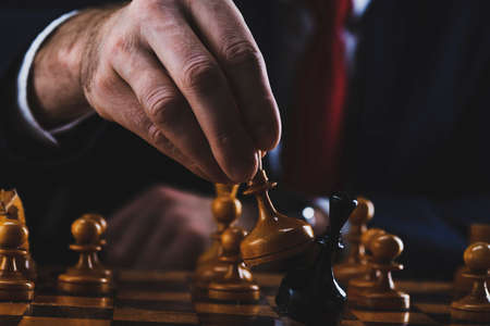 concept of strategy and business planning, businessman behind a chessboard white queen beats a black chess piece, strategy and tactics, readiness for battle, start of battleの写真素材