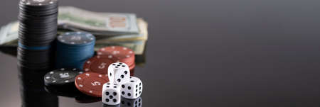 Chips, cards and dice for a casino game on a black background with reflection. The concept of gambling and entertainment. Casino and poker.の写真素材