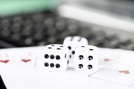 Online gaming platform, casino and gambling business. Cards, dice and multi-colored game pieces on laptop keyboard.の写真素材