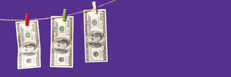 American dollars are dried on a rope on a purple background with place for text.の写真素材