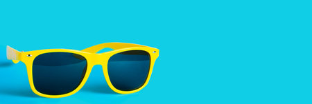Yellow sunglasses on blue background, concept of travel and vacation at sea.