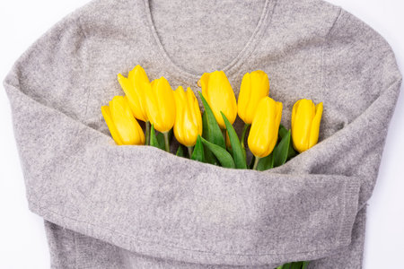 Bouquet of yellow tulips on a white background knitted sweater, top view, bouquet of yellow tulips...
