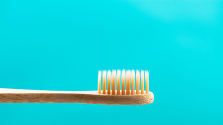 Environmentally friendly natural bamboo toothbrush on blue background. Health care, copy space
