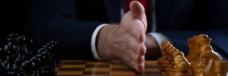 Strategy and business planning concept. A businessman at a chessboard in front of lined up white and...