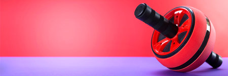 Abdominal roller, abdominal exercises, strength trainer on a mat on a red background, close up.の写真素材