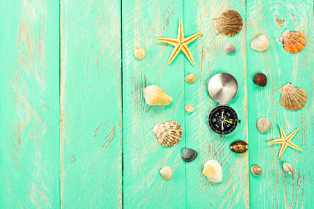 Seashells and compass on blue wooden table background. Summer vacation background, vacation and travel concept.の写真素材