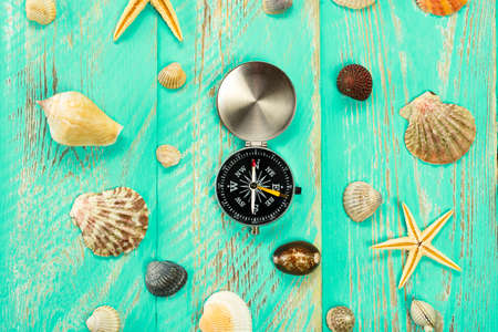 Seashells and compass on blue wooden table background. Summer vacation background, vacation and travel concept.の写真素材