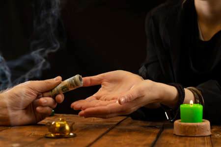 A fortune teller or oracle takes money for their work. Fortune telling by hand, geromancy. Psychic readings and the concept of clairvoyance.の写真素材