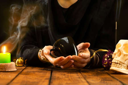 Fortune teller with a black cup in hand for fortune telling on the coffee grounds. Psychic readings and the concept of clairvoyance.の写真素材