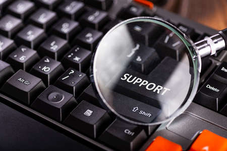 Magnifying glass on key support for black computer keyboard. Technical support.の写真素材