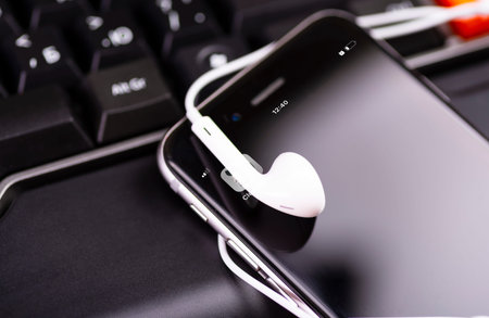 A modern smartphone and headphones are on the keyboard. Social audio network Clubhouse.