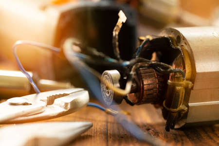 Power tool repair. Details of electrical appliance and repair tools on a wooden table in a repair shop.の写真素材