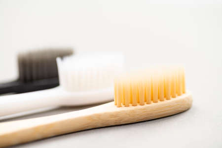 Natural eco-friendly bamboo toothbrush and two plastic toothbrushes on a white background close-up. Choose a plastic or wooden toothbrush. Recycling concept, no waste, no plastic, top view.の写真素材