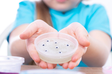 White transparent mucus on the hands of the child. Add many small eyes to the slime. Play toy -...