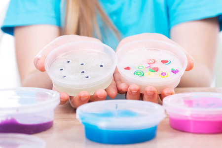 The child plays with slimes. The girl shows her slimes in her hands. Play Slime Toy.