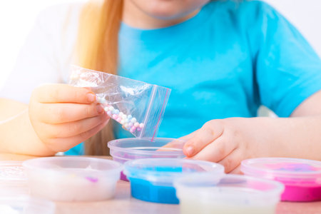 The child plays with many slimes. Put balls in slime, toy - slime.の写真素材