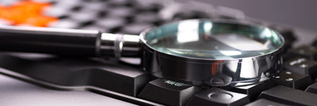 Magnifying glass on the keys of a black computer keyboard.