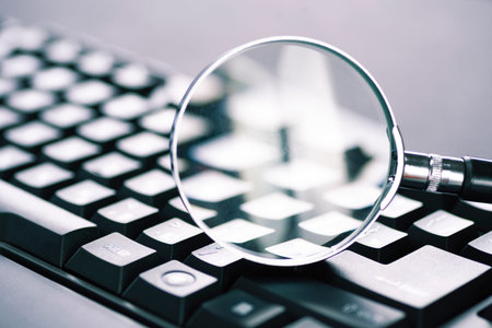Magnifying glass on the keys of a black computer keyboard.の写真素材